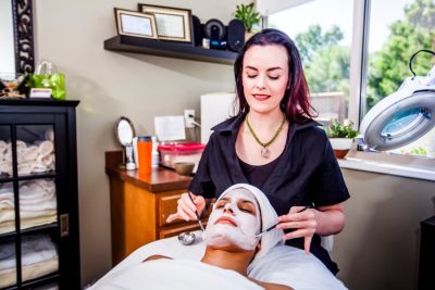 A woman receives a beauty mask treatment from an esthetician